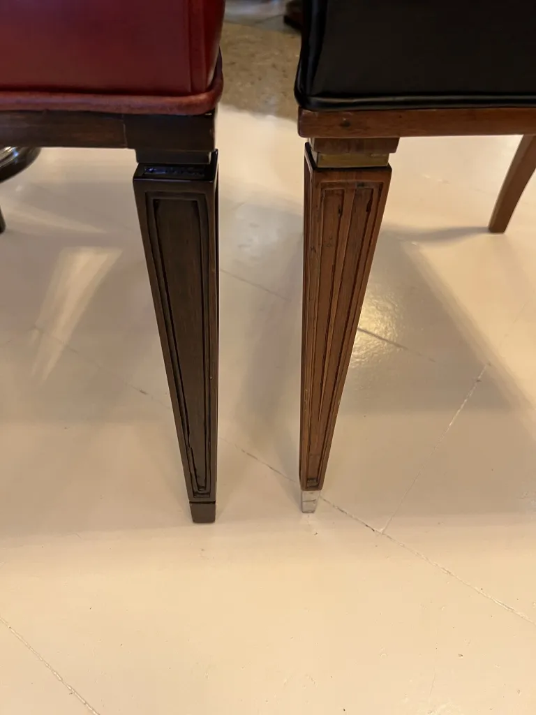 Visão de duas cadeiras antigas elegantes, uma vermelha e outra preta, em um ambiente acolhedor.