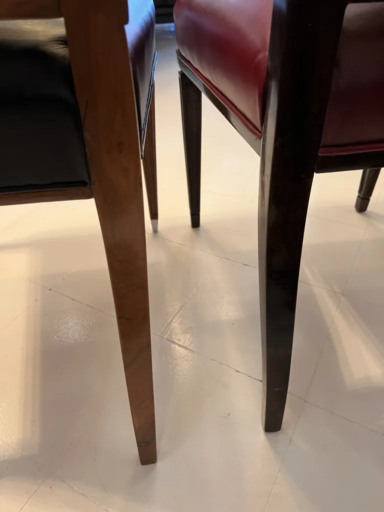 Vista de 12 cadeiras antigas, com detalhes em preto e vermelho, em um ambiente elegante.