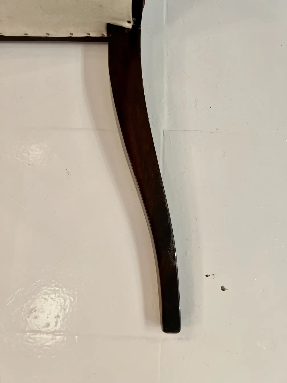 detalle de una silla antigua con patas curvas sobre fondo blanco