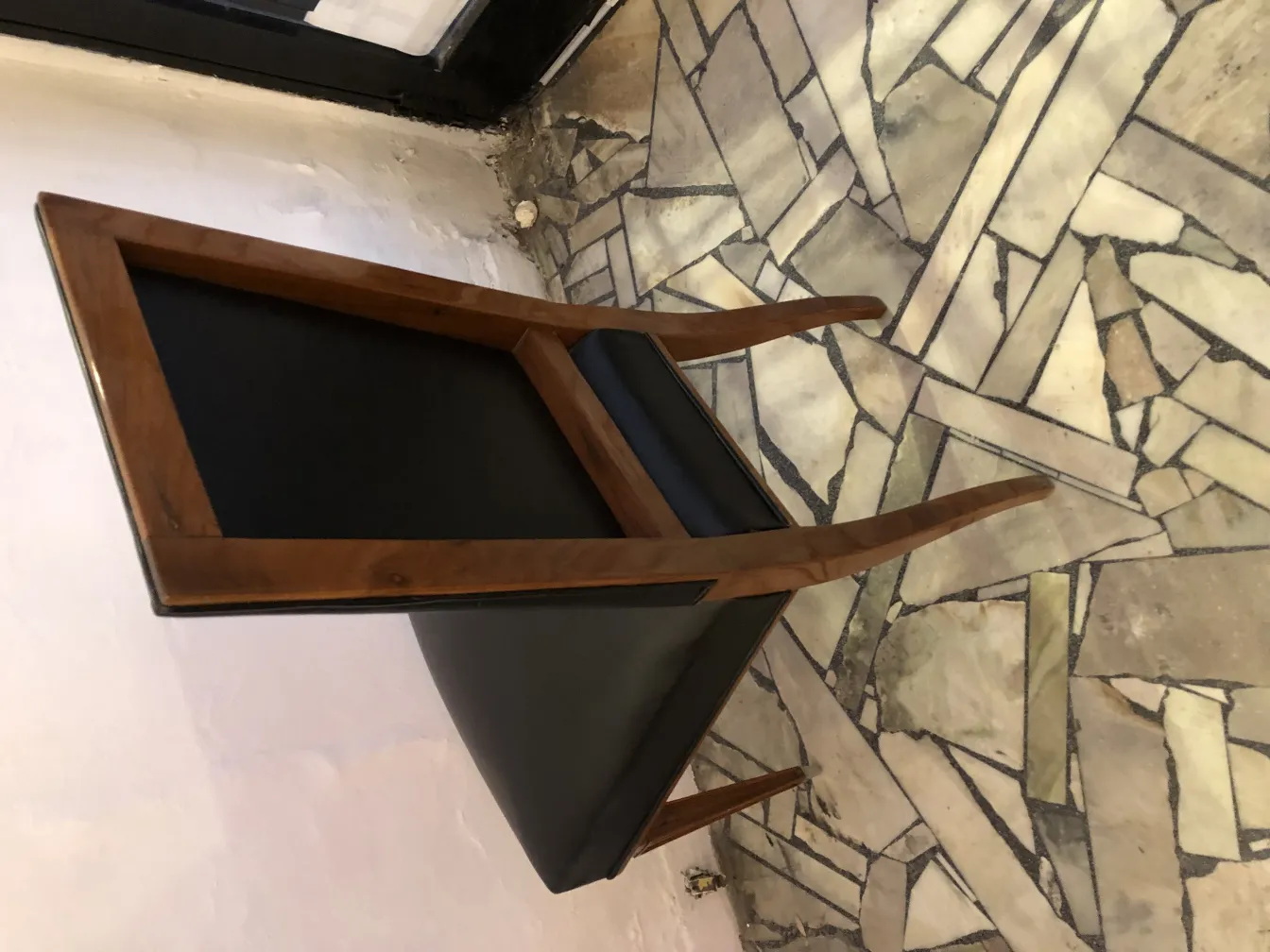 Side view of 12 antique chairs on a light stone floor