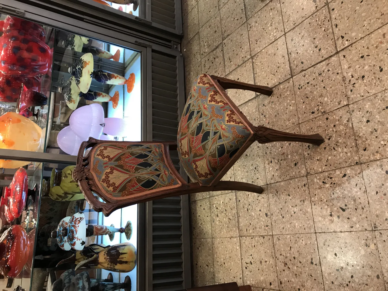 Chaise antique décorative avec design coloré, fond avec des vitrines en verre.