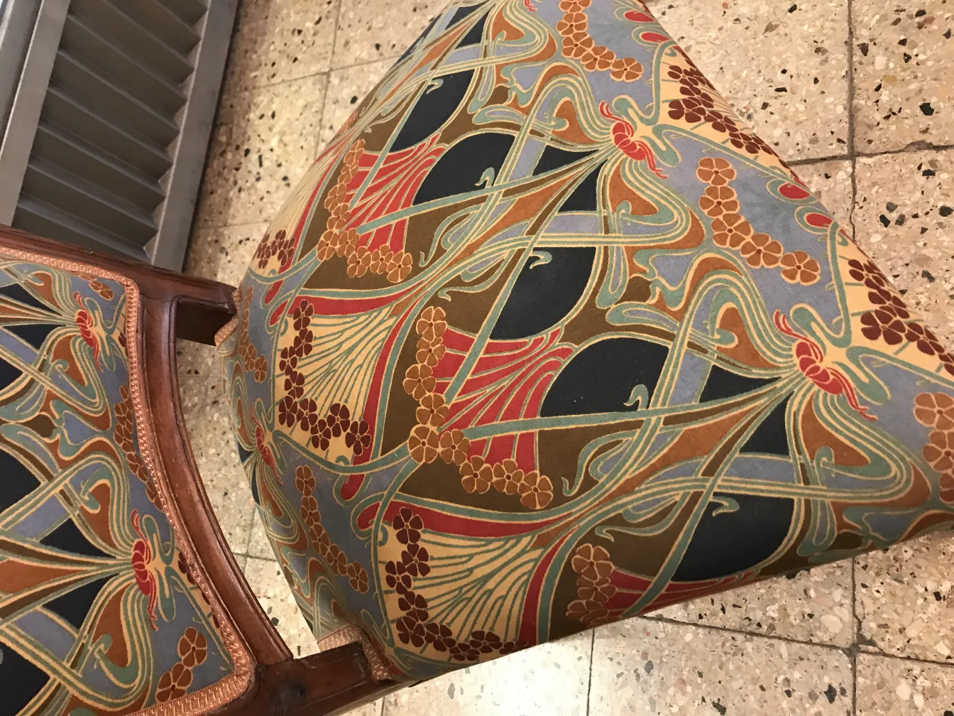 Antique chair with colorful floral design, cozy environment.