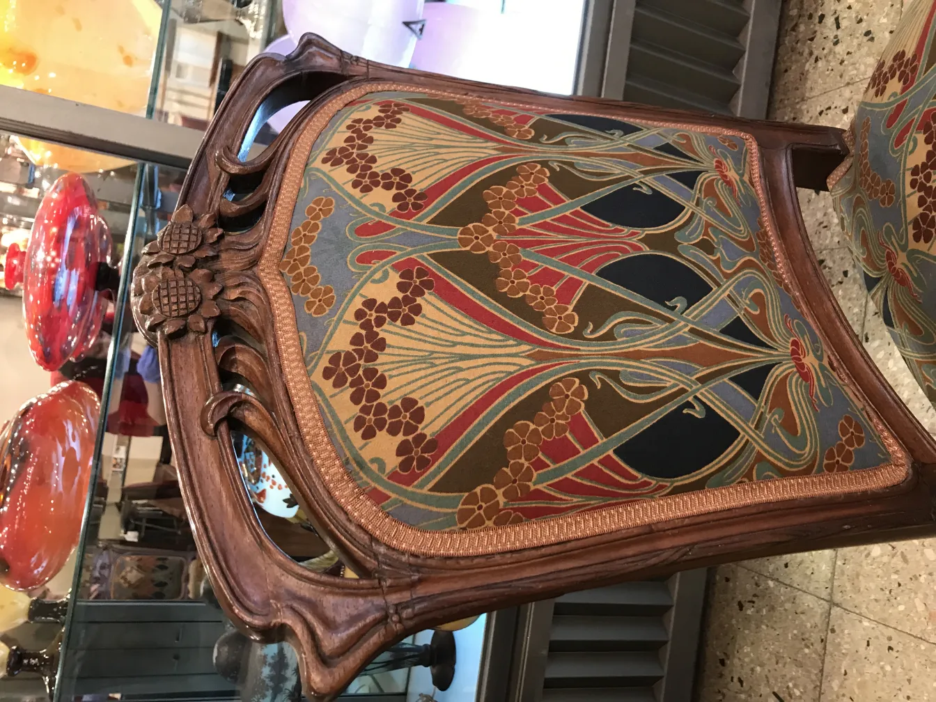 Silla antigua con diseño colorido en una tienda de antigüedades.