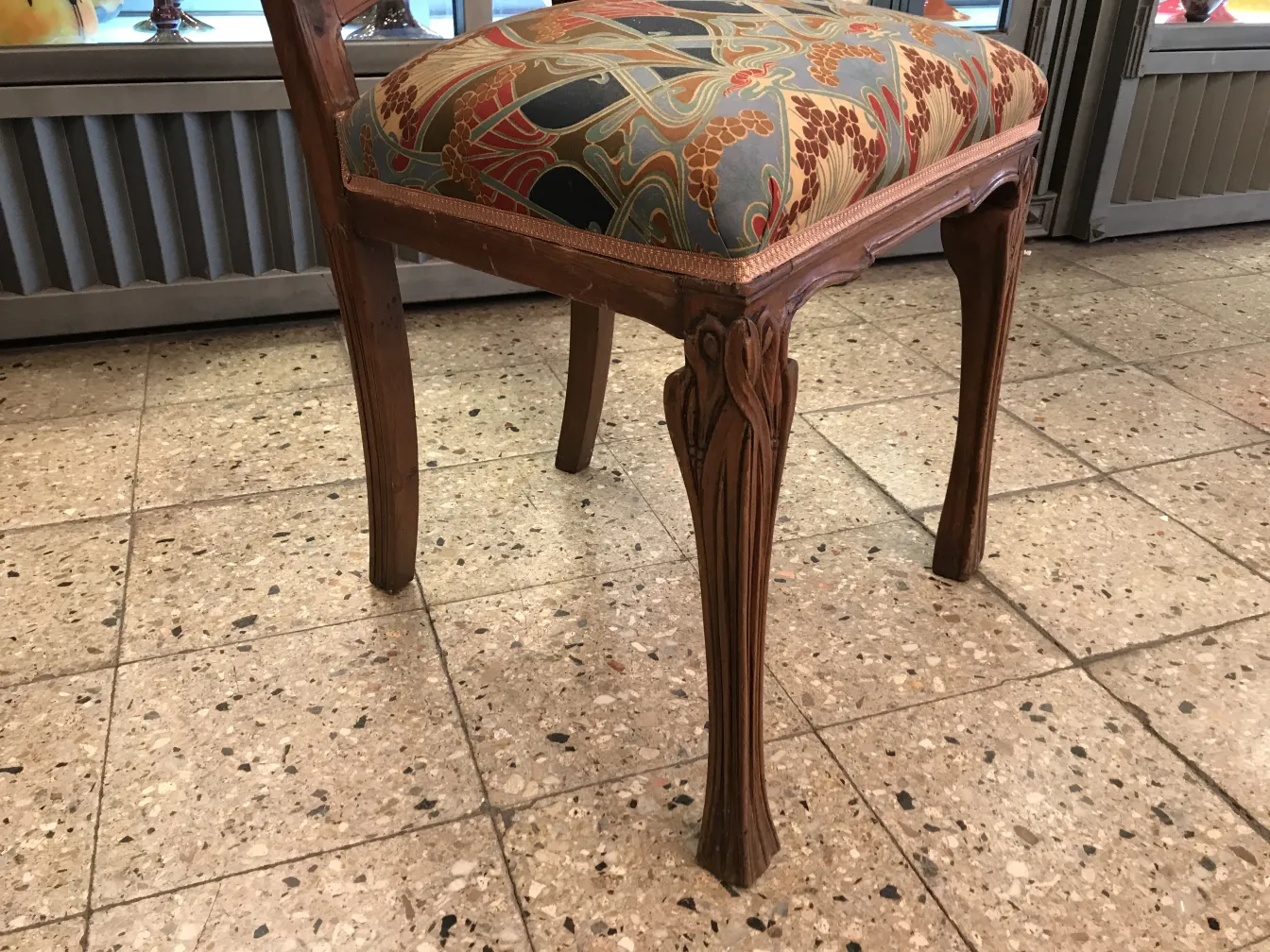 Chaise antique décorative avec un bel rembourrage et des pieds fins, dans un environnement accueillant.