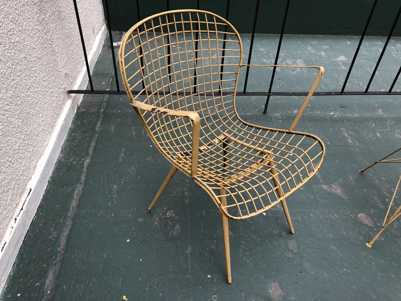 Fauteuil de jardin ancien jaune dans un environnement extérieur.