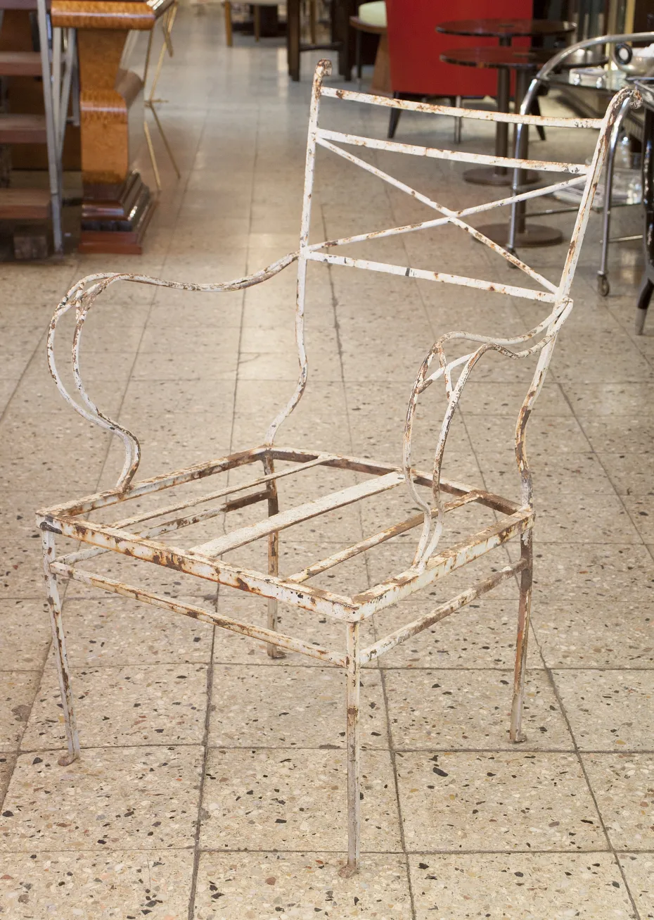 Fauteuil de jardin ancien avec structure visible dans un grand espace.