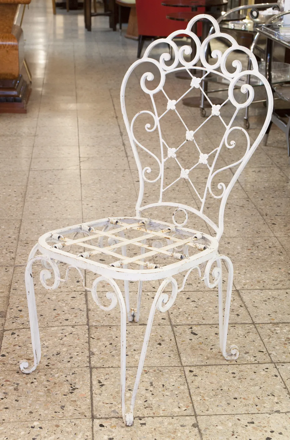 Deux chaises de jardin anciennes, blanches, avec un design élégant et des détails décoratifs, placées dans un environnement accueillant.