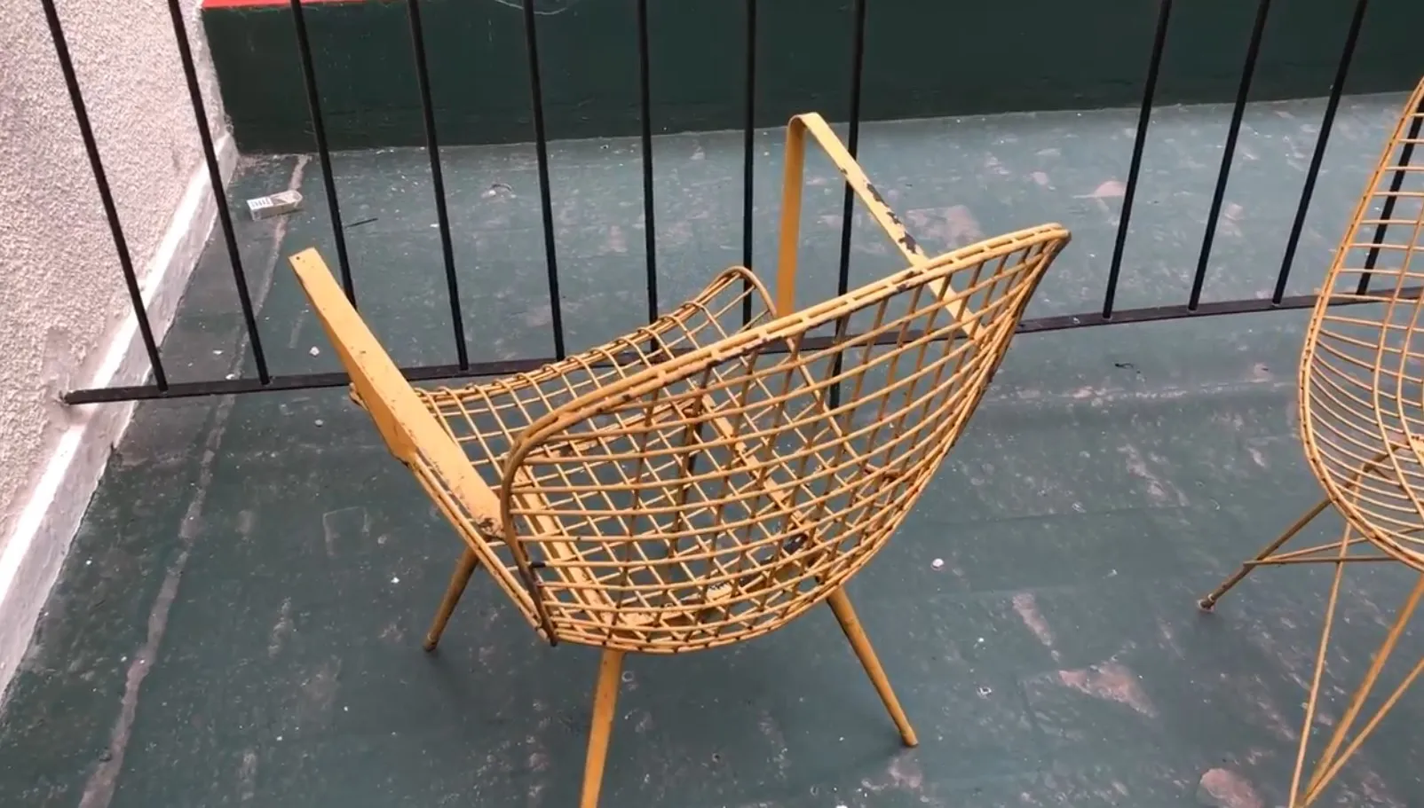 Two antique yellow garden armchairs on a balcony with railing.