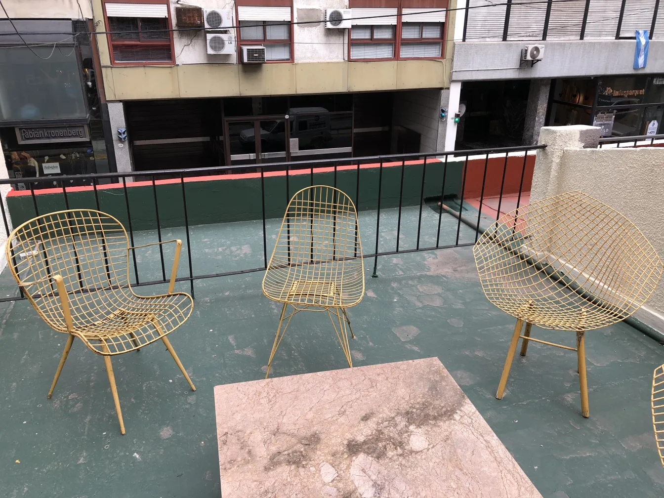 Zwei antique gelbe Garten-Sessel auf einer Terrasse mit Blick auf die Straße
