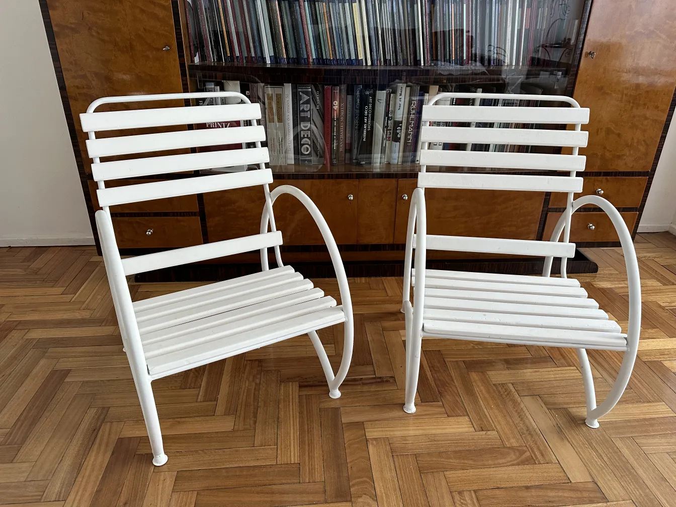 Deux fauteuils de jardin anciens de couleur blanche dans un environnement intérieur avec un sol en bois.