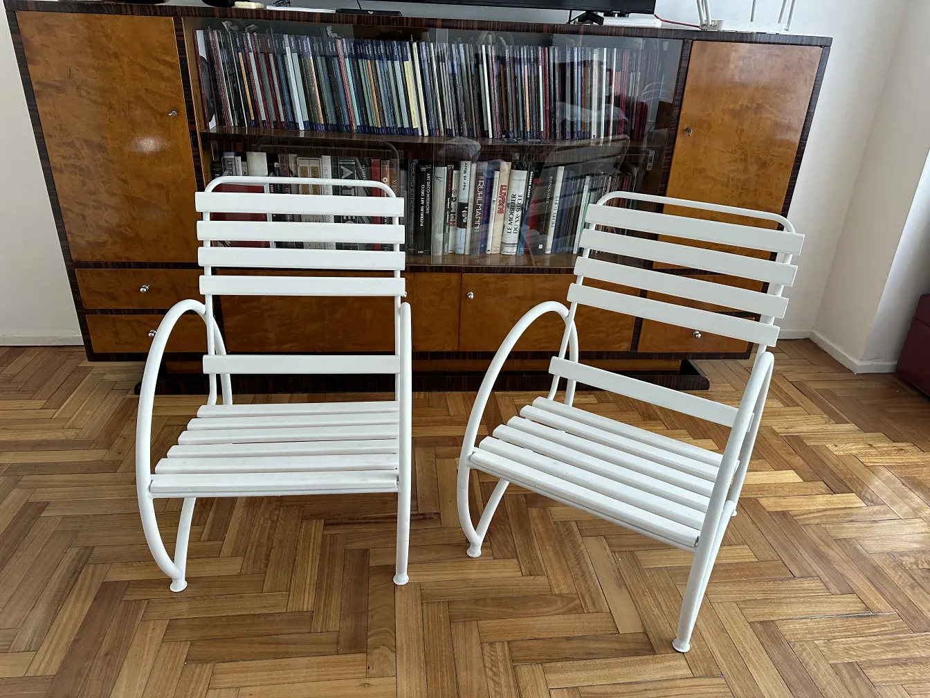 Antiguos sillones de jardín de color blanco, con líneas elegantes, en un ambiente acogedor.