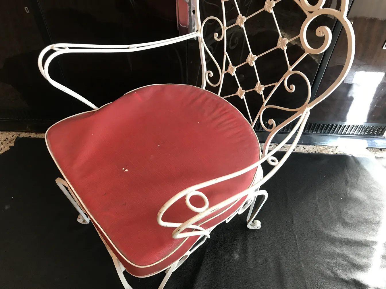 Ancien fauteuil de jardin avec assise rouge dans un cadre simple
