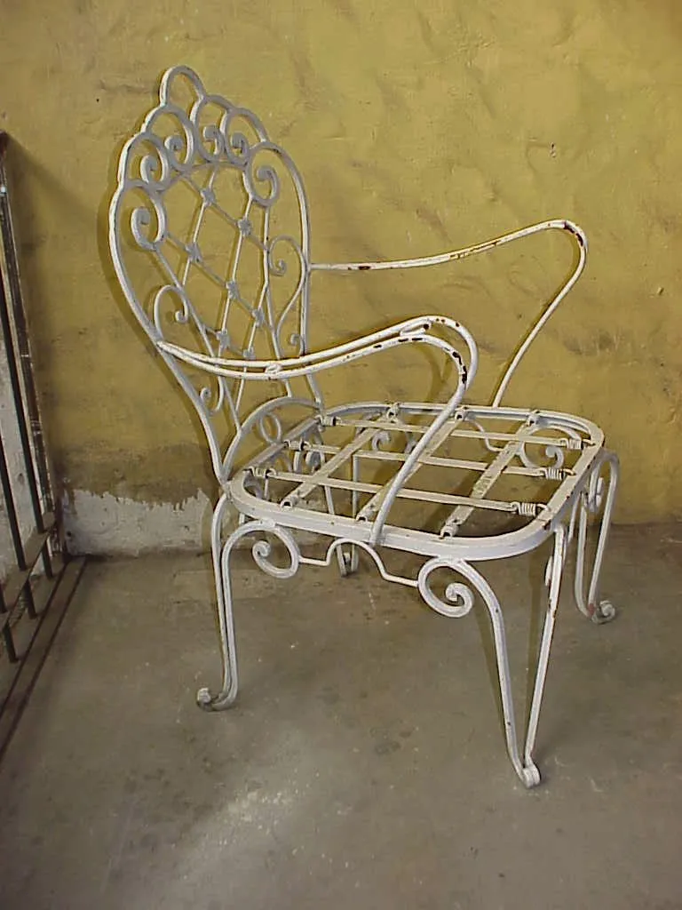 Dos sillones de jardín antiguos con detalles decorativos y elegante forma, en un ambiente rústico.