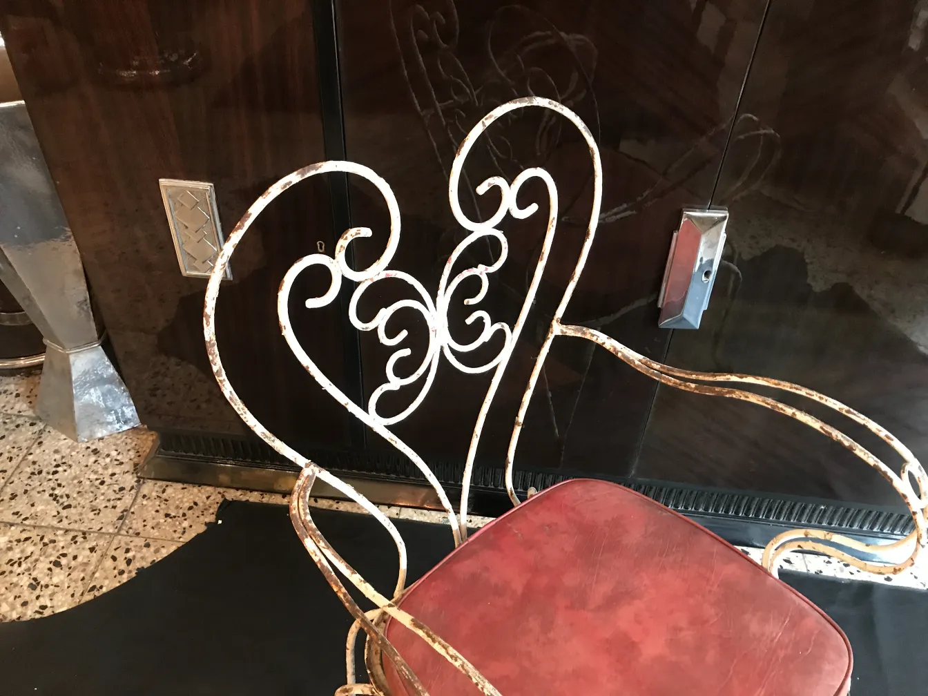 Três poltronas de jardim antigas com encostos decorativos em um ambiente aconchegante