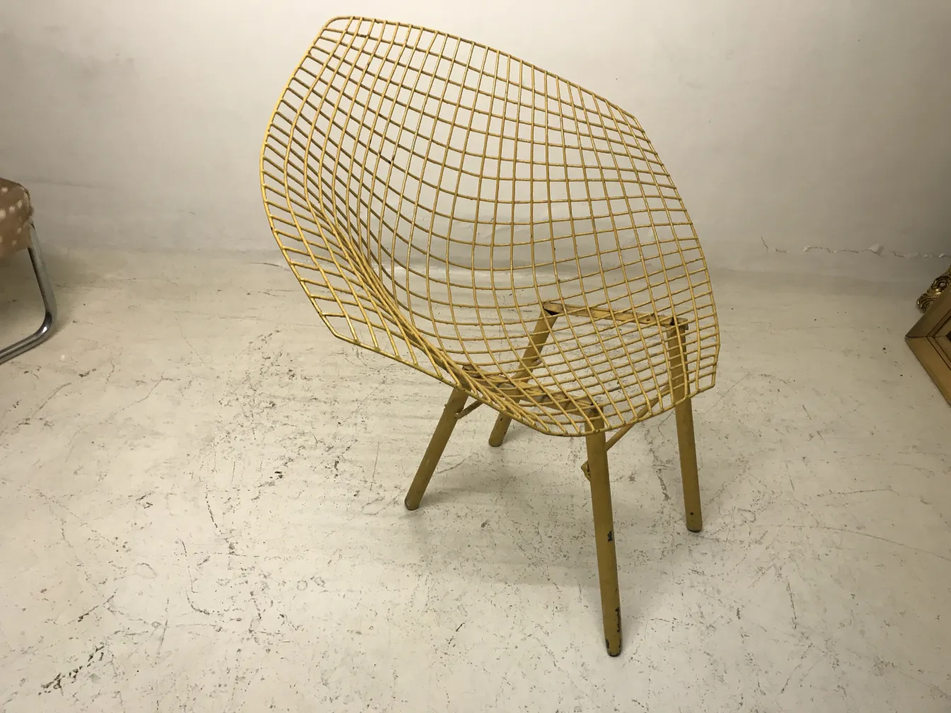 Tre poltrone da giardino antiche con design a rete gialla in un ambiente minimalista.