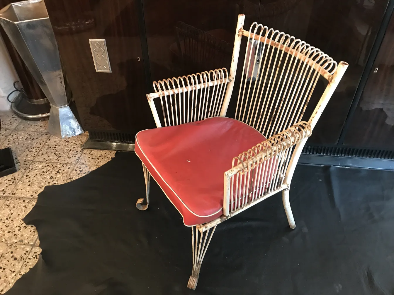 Quatro poltronas de jardim antigas com almofadas vermelhas em um ambiente clássico.