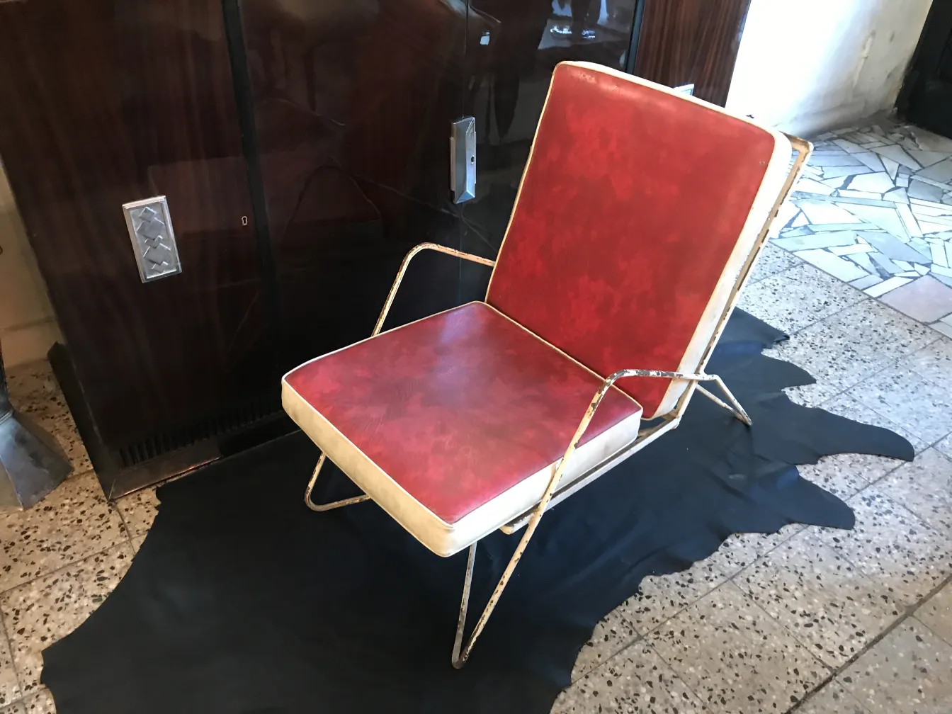 Cuatro sillones de jardín antiguos con marco de metal y almohadones rojos, en ambiente elegante