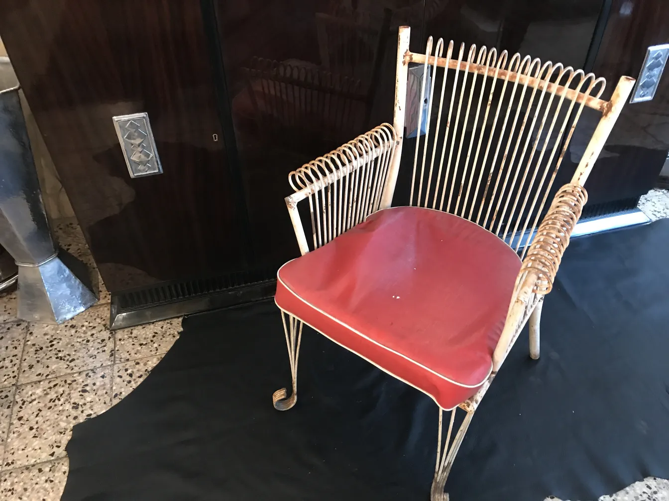Quatre fauteuils de jardin anciens avec coussins rouges dans un cadre élégant.