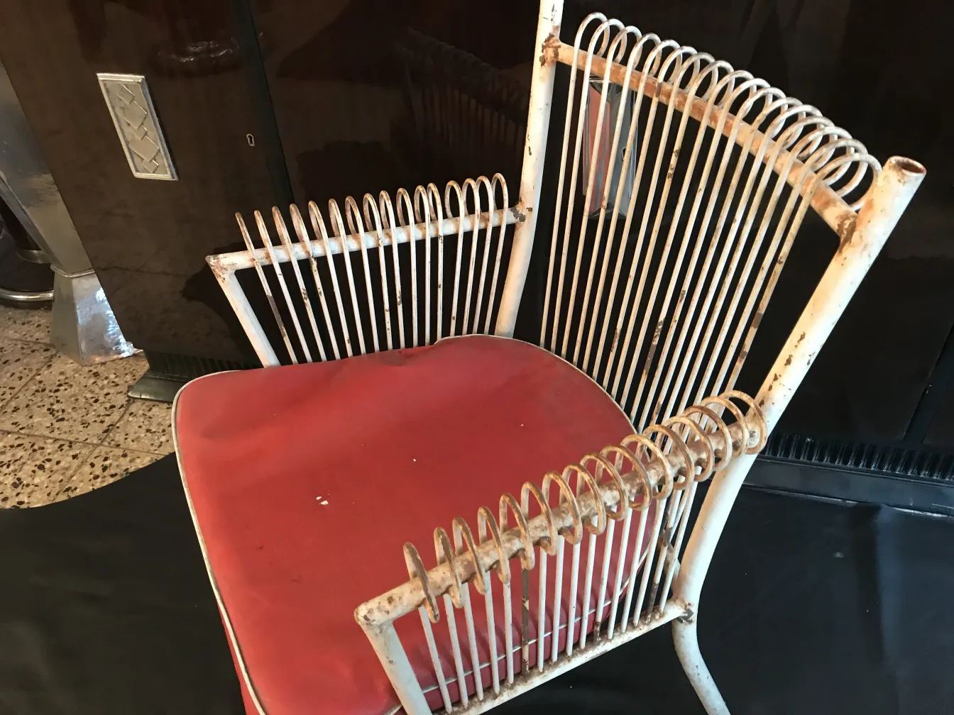 Sillones de jardín antiguos con estructura blanca y cojín rojo, ambiente clásico.