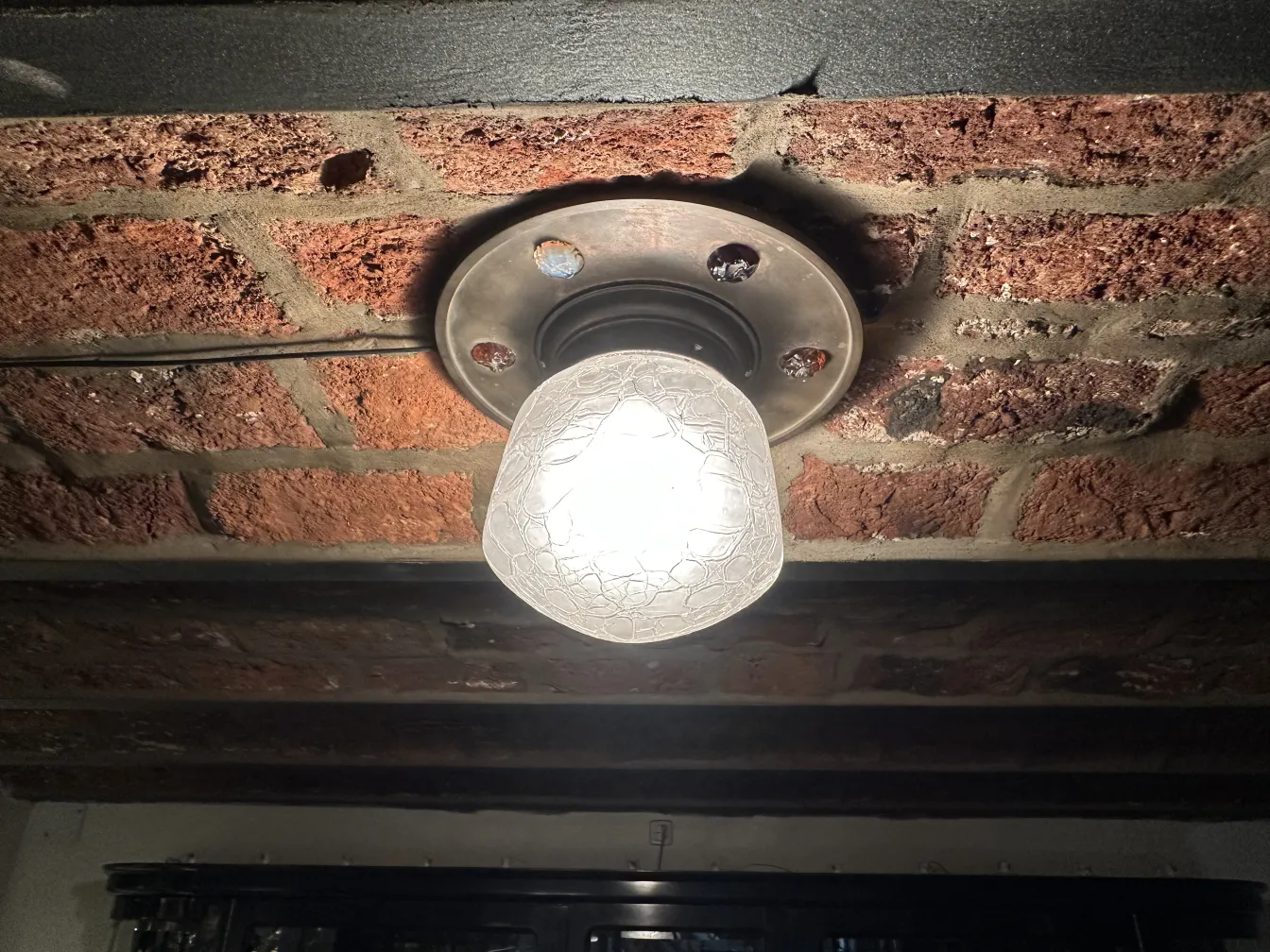 plafoniera antica con illuminazione brillante su soffitto di mattoni