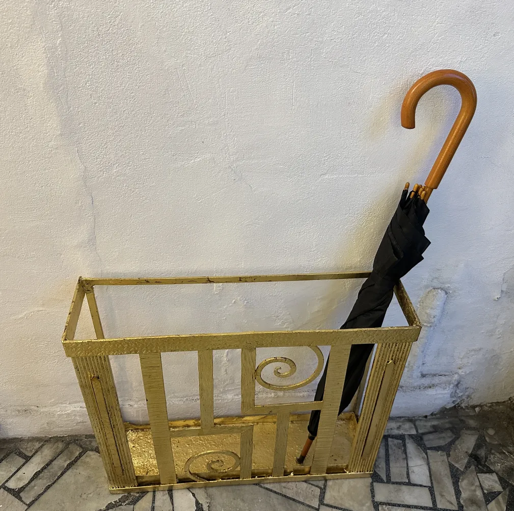 porte-parapluie ancien doré avec un parapluie noir