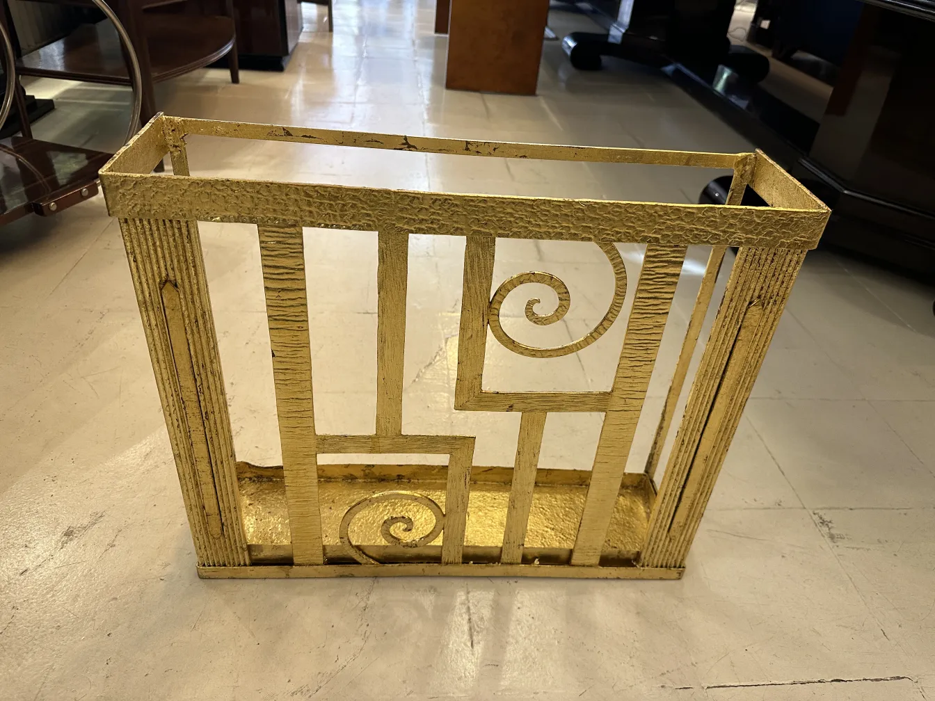 Antiker goldener Schirmständer mit spiralförmigem Design in einem eleganten Ambiente.