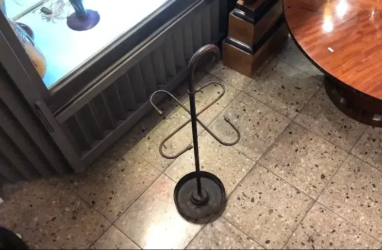Antique umbrella stand with circular black base, modern environment.