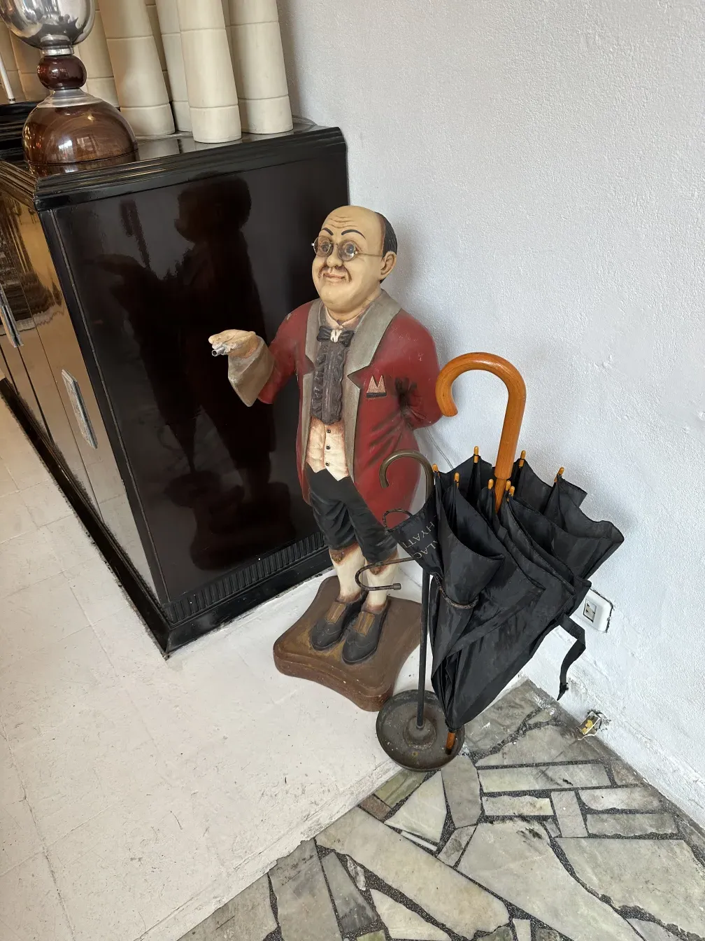 Paragüero antiguo con figura decorativa de un hombre y sombrero.