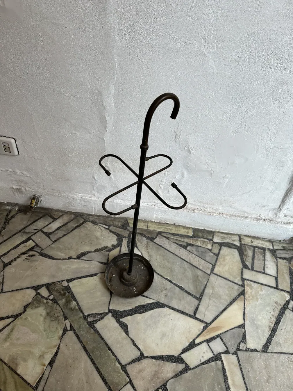 Antique umbrella stand with distinctive details in a neutral setting.