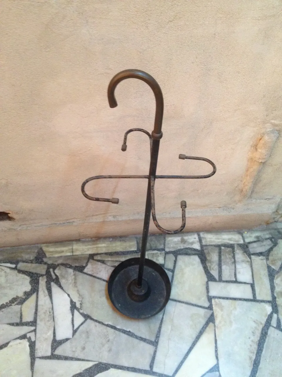 antique umbrella stand with curved design, circular base, neutral setting