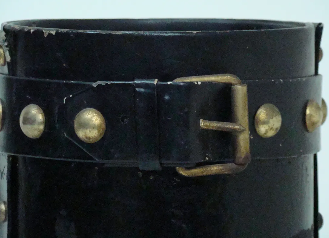 Ancien porte-parapluie noir avec détails dorés et design classique.