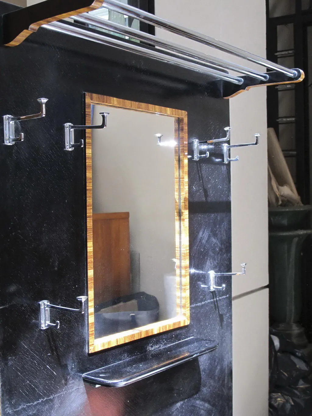 antique coat rack with mirror, hooks, and dark background