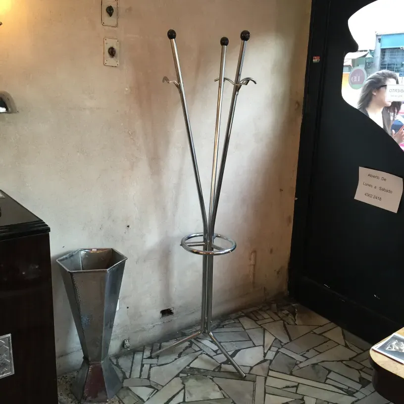 Bengaleiro antigo com design elegante, ganchos e base circular em ambiente neutro