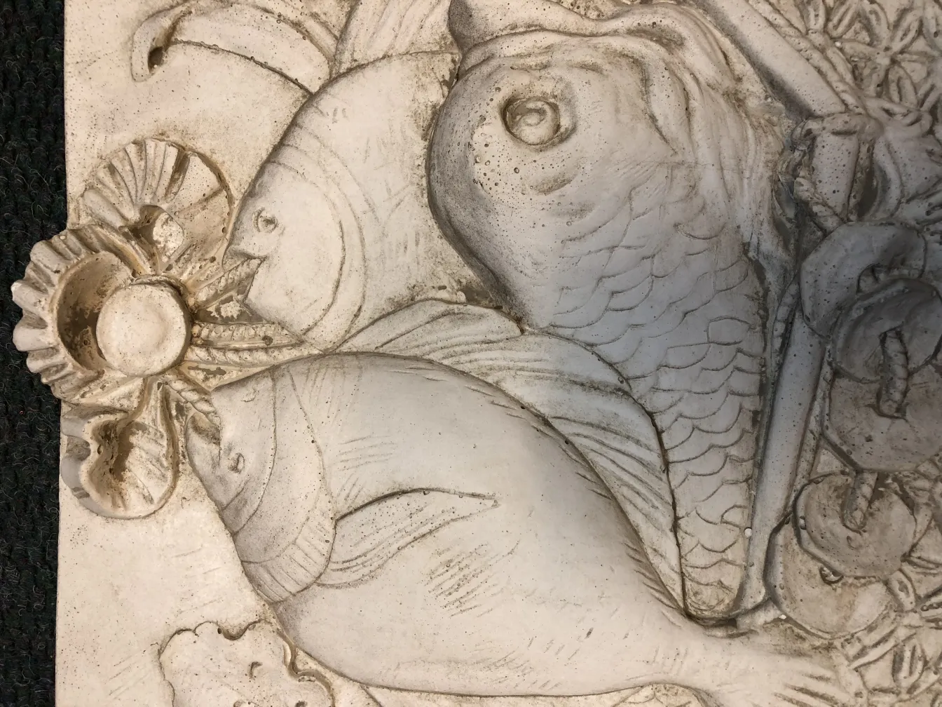 Antike Wandplatte dekoriert mit Fischen und Muscheln.