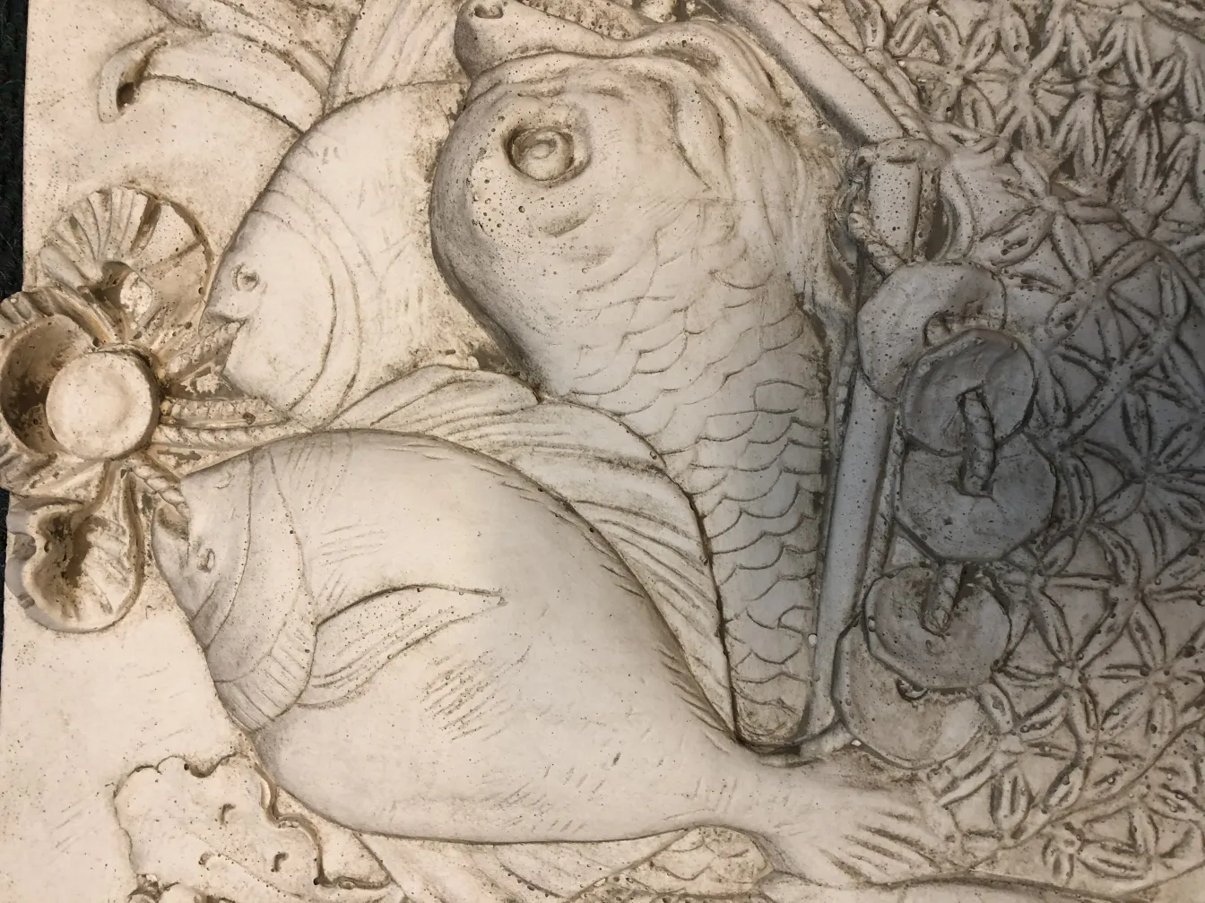 plaque murale ancienne avec des reliefs de poissons et des détails complexes