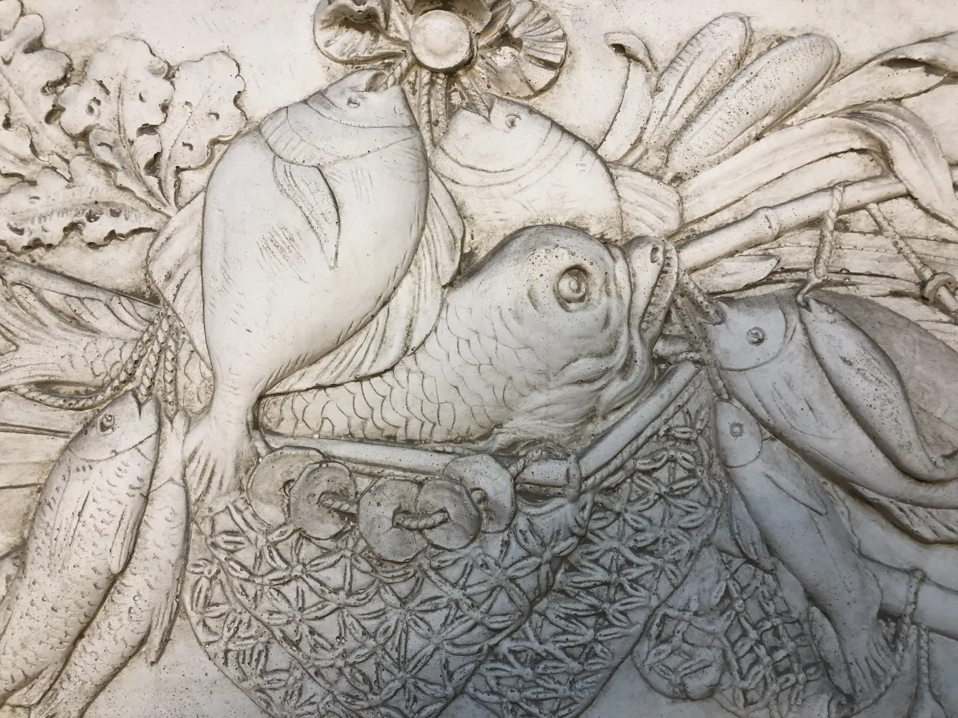 detail of an antique wall plate featuring various fish and leaves