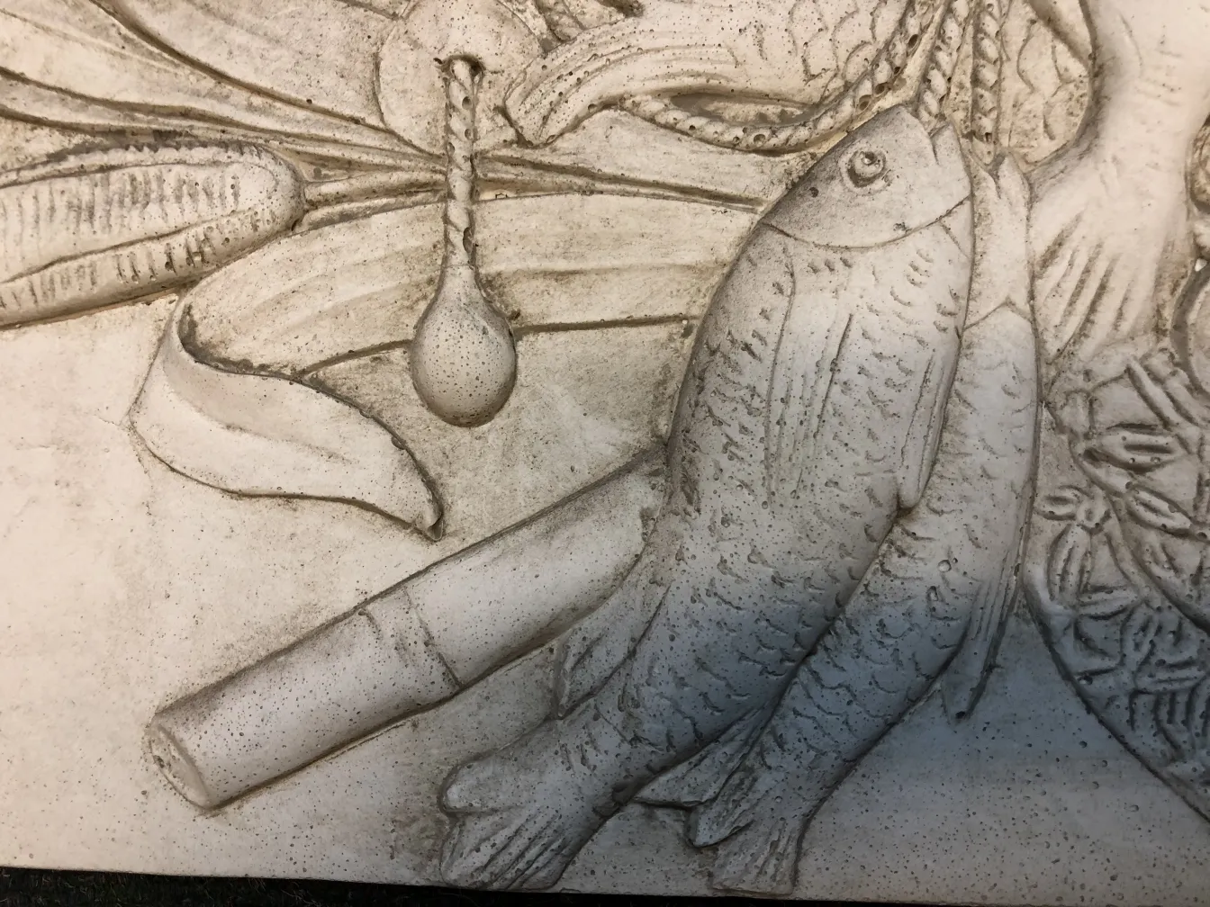 detalle de una antigua placa de pared con pescados y vegetación