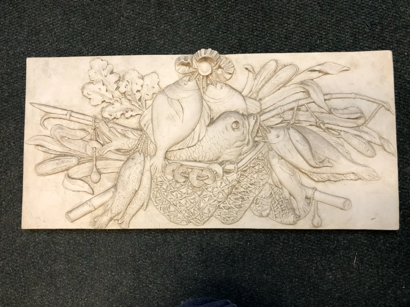 古老的墙板，展示雕刻的蔬菜和鱼。