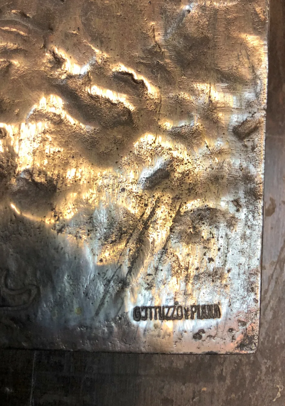 Placa de pared antigua con texturas y firma visible