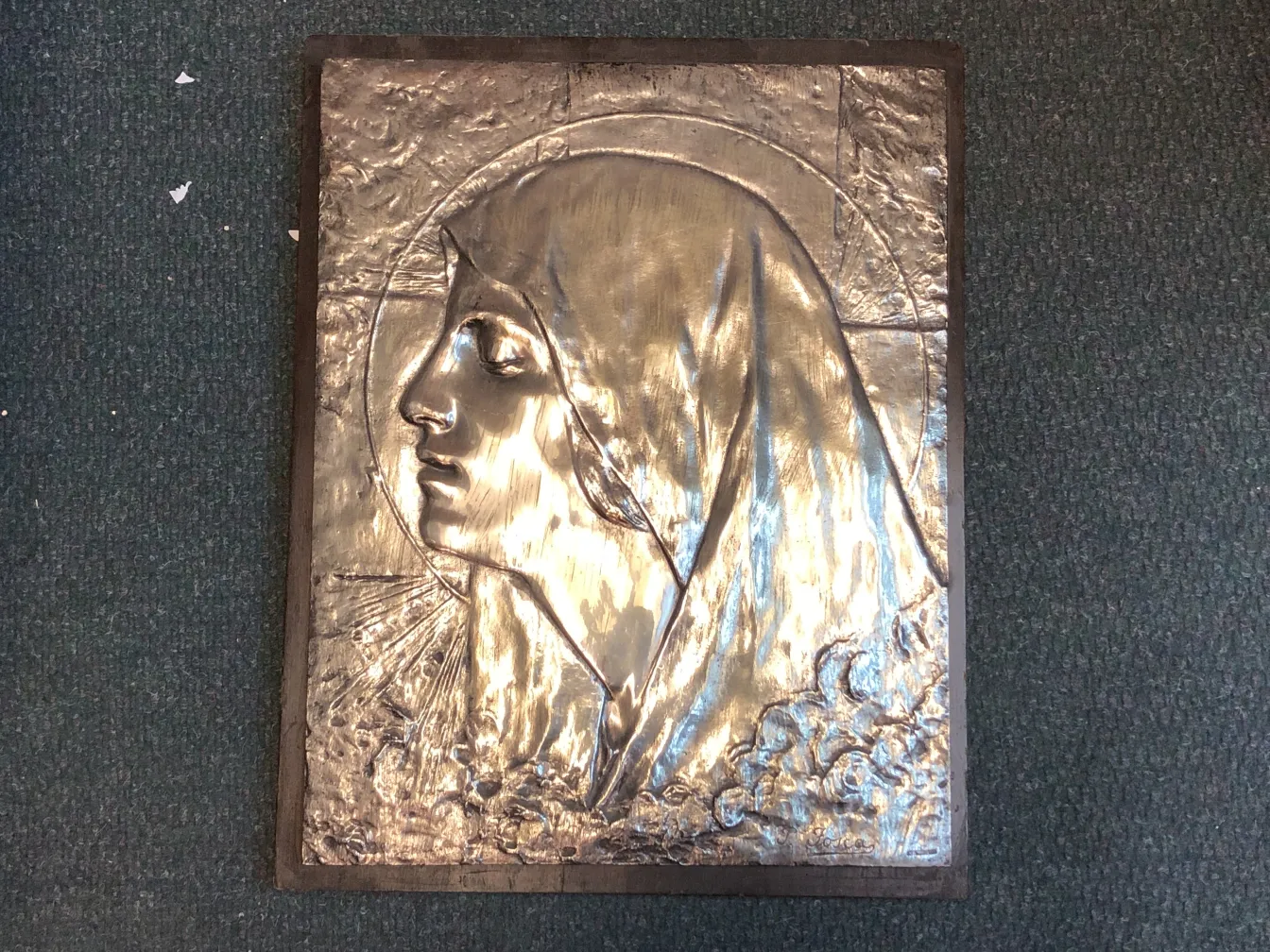 Placa de pared antigua con un retrato de rostro humano.