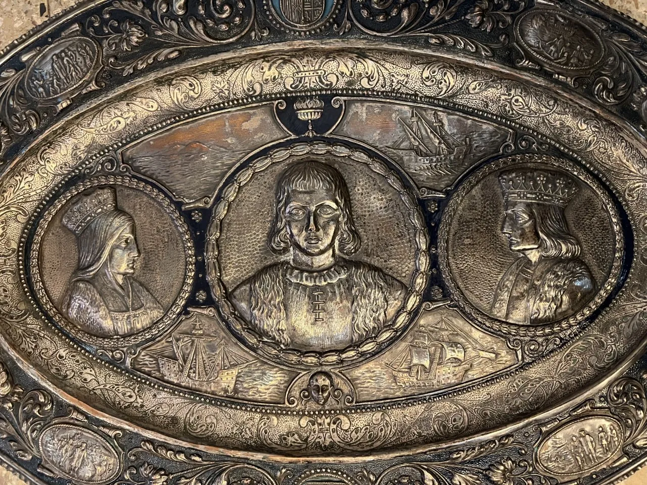 لوحة جدارية قديمة تحتوي على صور لأشخاص وسفن في تصميمها، مع خلفية زخرفية.