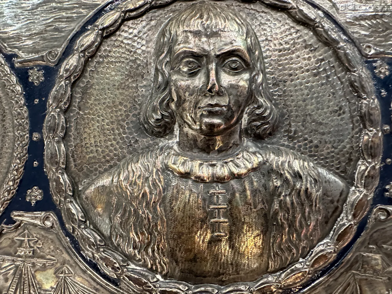 Antique wall plate featuring a raised portrait and decorative details.