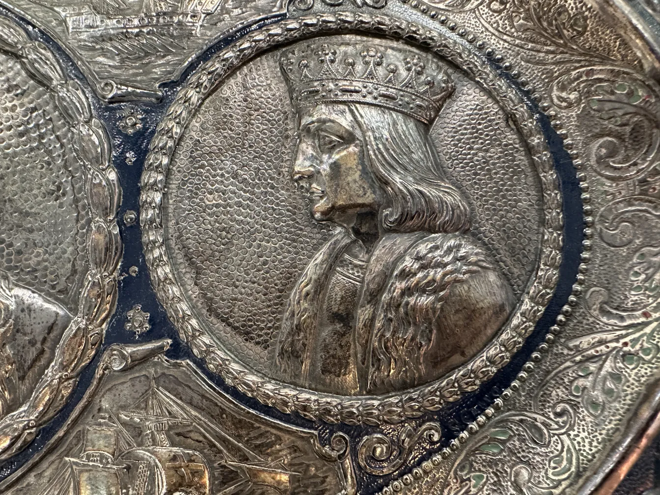 Placa de pared antigua con la imagen de un rey y detalles ornamentales.