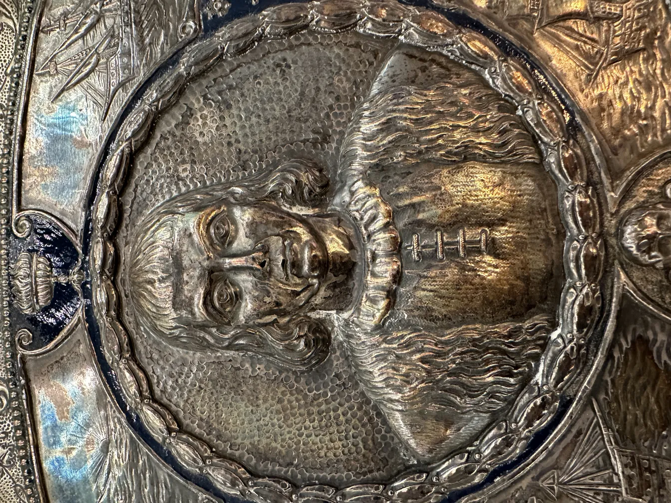 Placa de parede antiga com retrato esculpido, detalhes ornamentais, fundo suave.