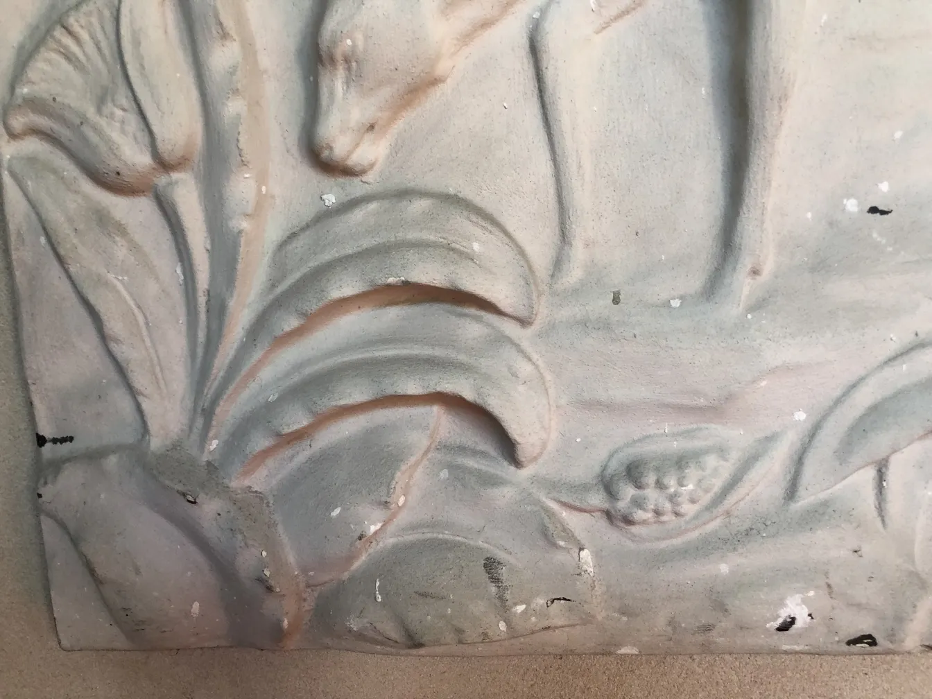 détail d'une plaque murale ancienne avec des reliefs de feuilles et de fleurs