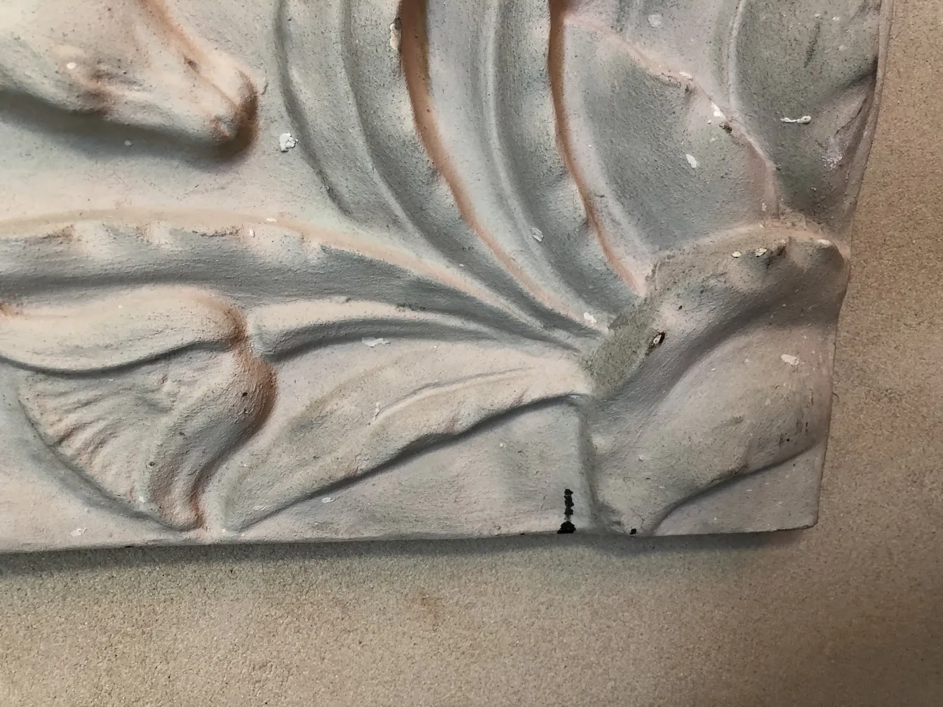 Plaque murale ancienne avec des détails en relief, présentant des décorations douces et des motifs élégants.