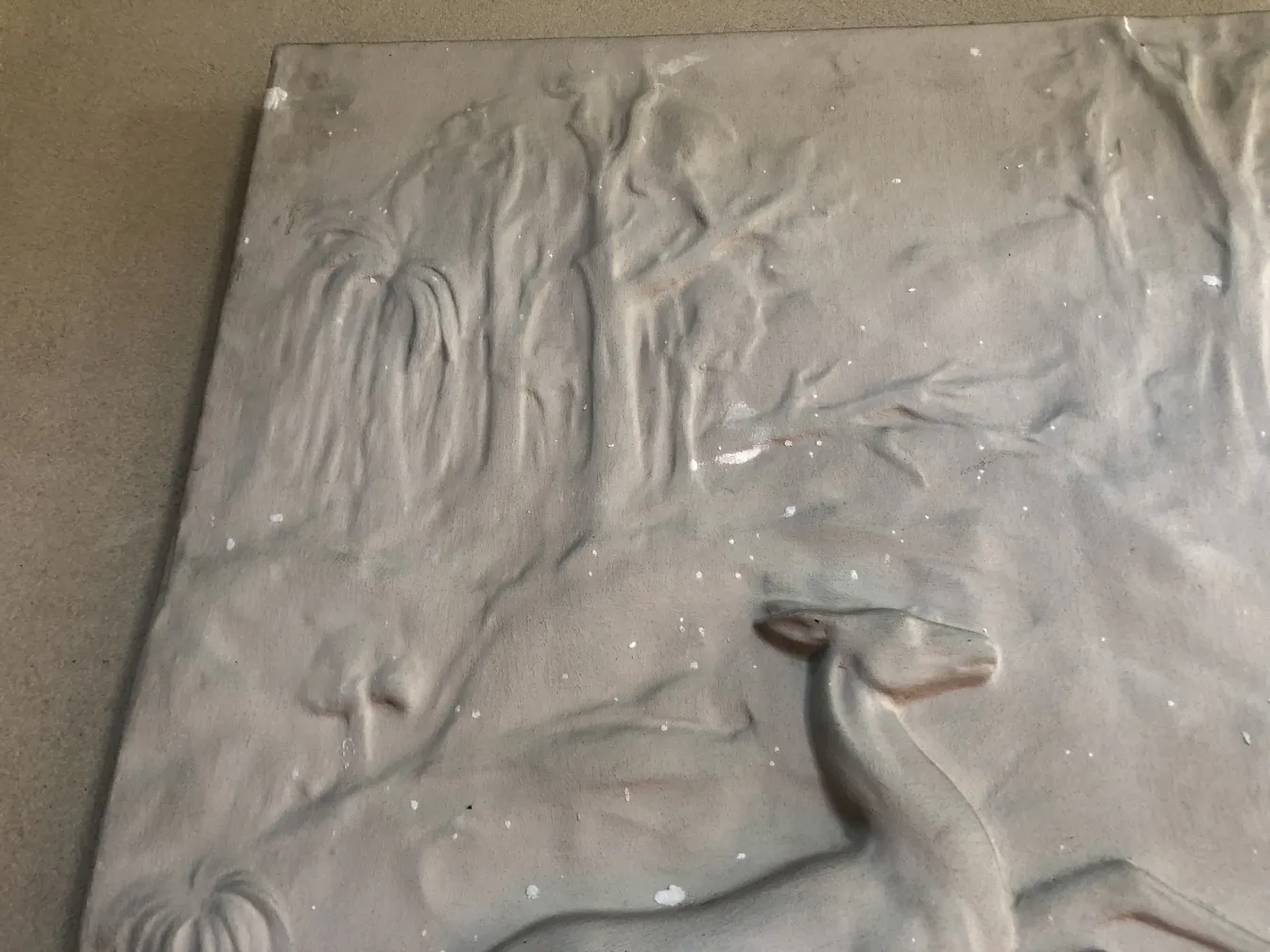 Placa de pared antigua con diseño naturalista y ciervo.