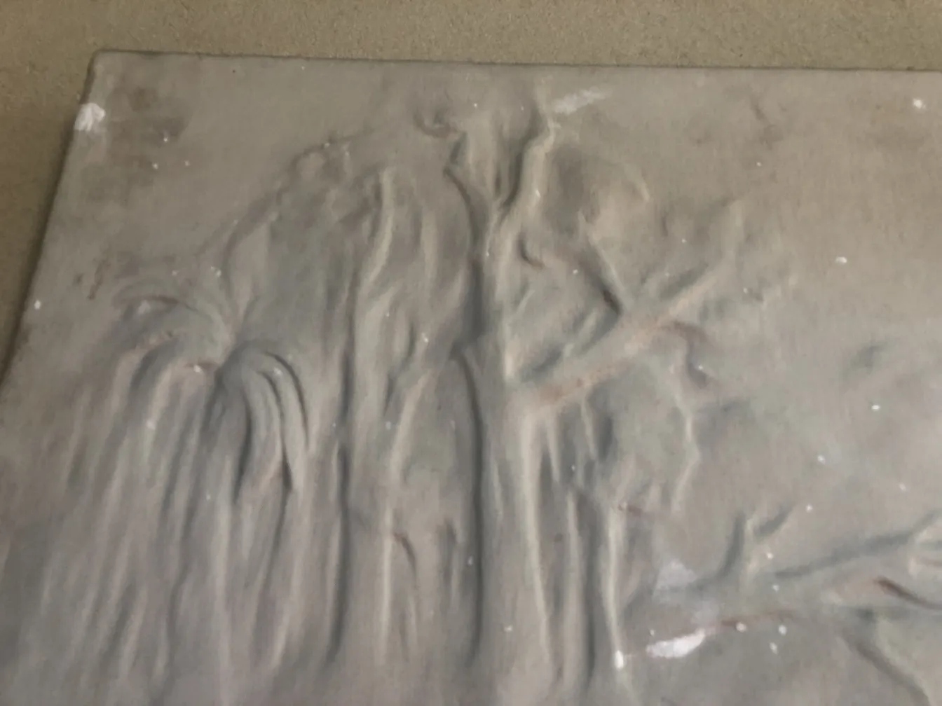 Antique wall plate featuring relief details and texture.