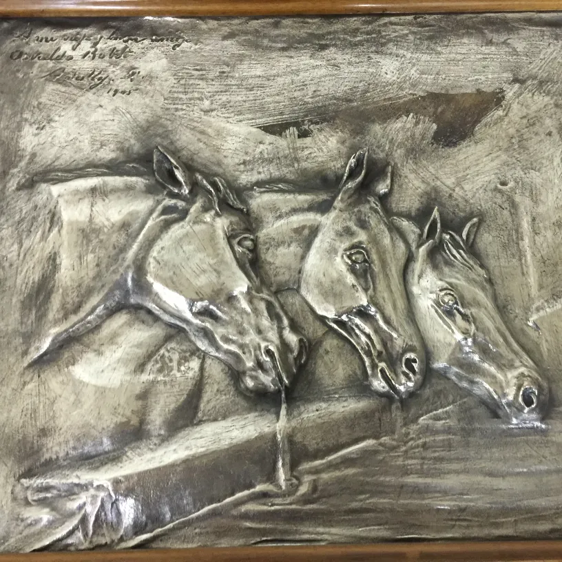 antique wall plate featuring three horse heads in relief, light background, classic setting