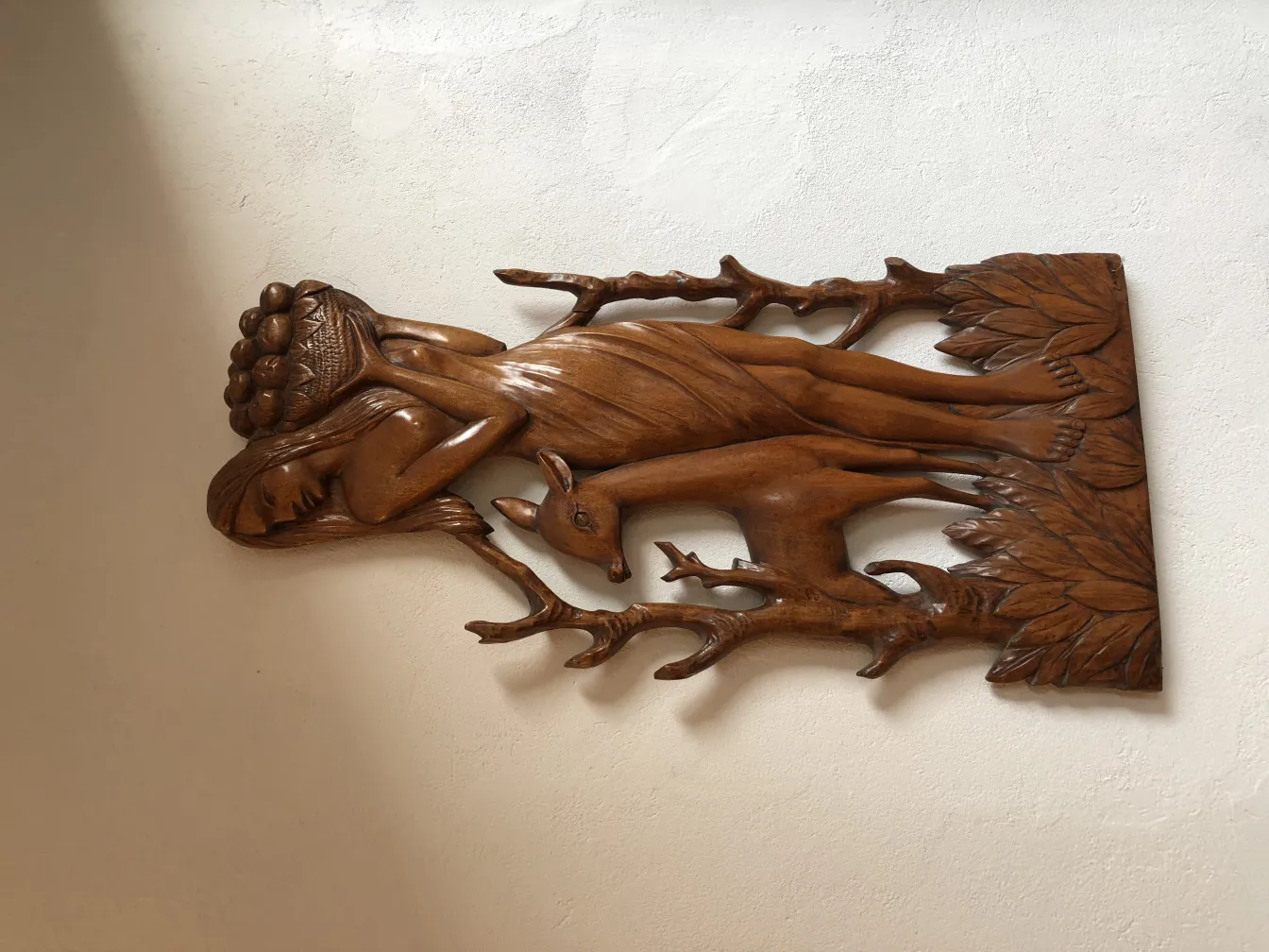 Placa de pared antigua con relieve de figura humana y ciervo.